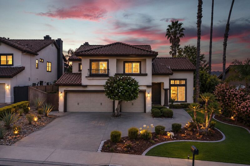 Twilight exterior of a single-story home with lit landscaping