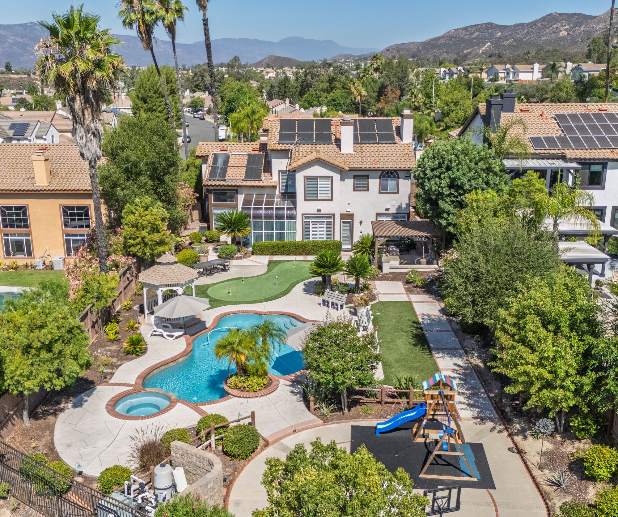 Aerial view of a landscaped backyard with a pool and spa