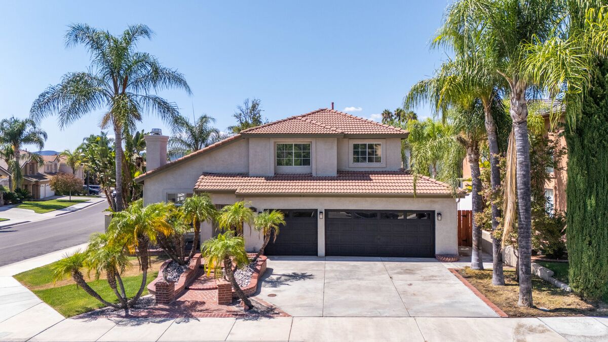 Aerial front view of a palm-lined two-story home