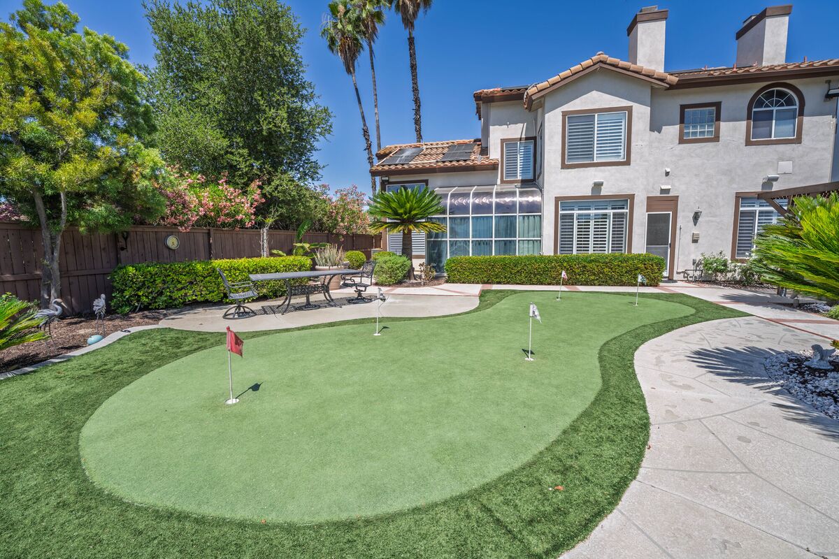 Landscaped backyard with a putting green and mature trees