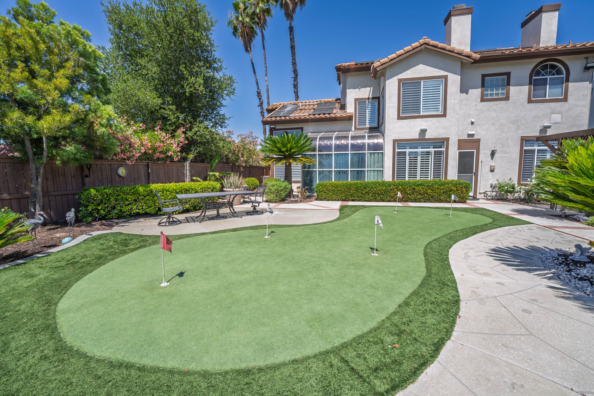 Landscaped backyard with a putting green and mature trees
