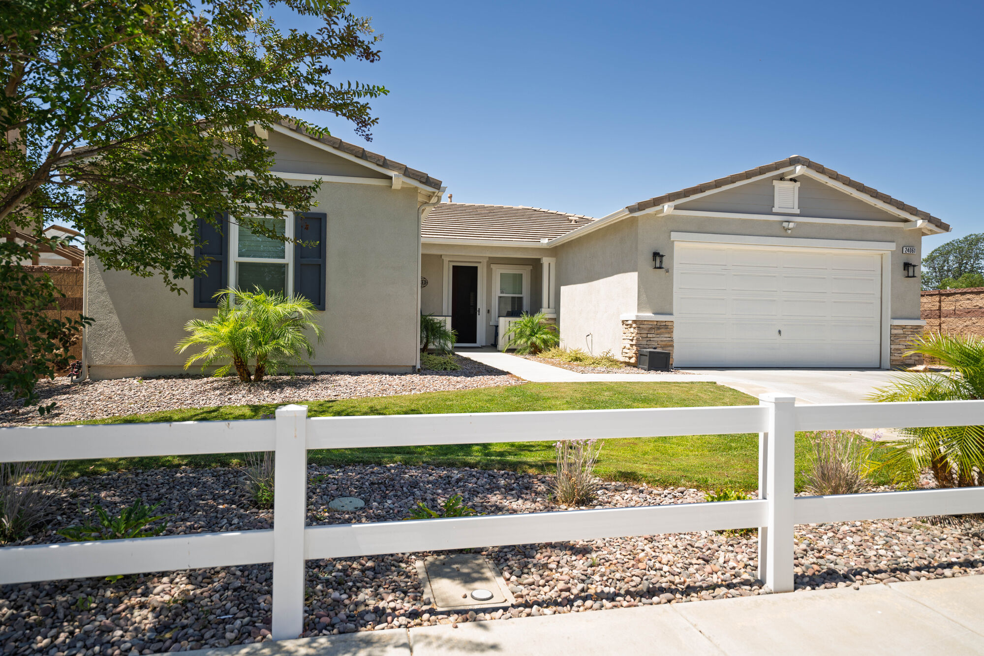 Front exterior of a single-story home behind a white fence