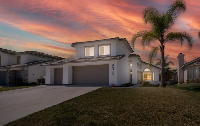 Twilight exterior of a home with palms and a warm evening sky
