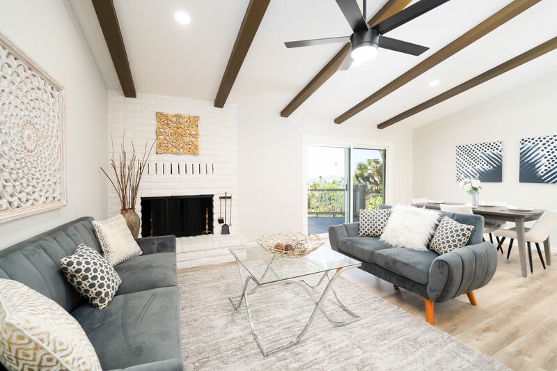 Bright living room with ceiling beams, a fireplace, and modern staging