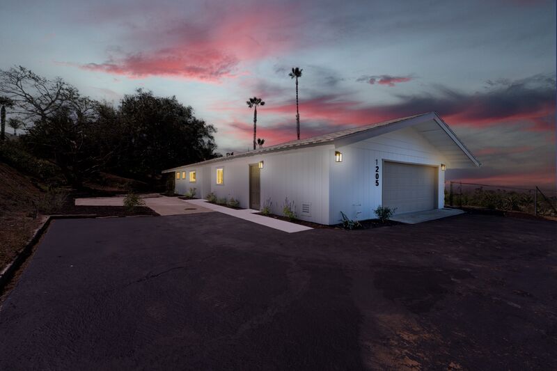Twilight exterior of a single-story home beneath pink evening clouds